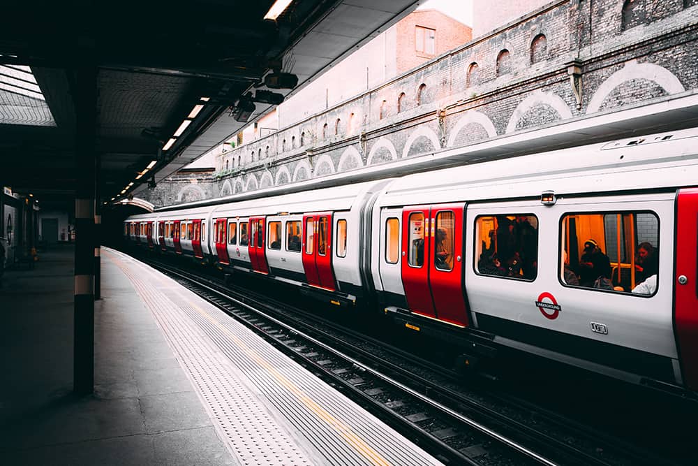 A red and white train filled with people is about to take off from the Sloane Square Station of London Tube