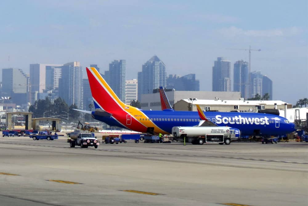 The tarmac at San Diego International Airport with the welcoming sight of the downtown skyline in the background and a Southwest Airlines plane at the gate.