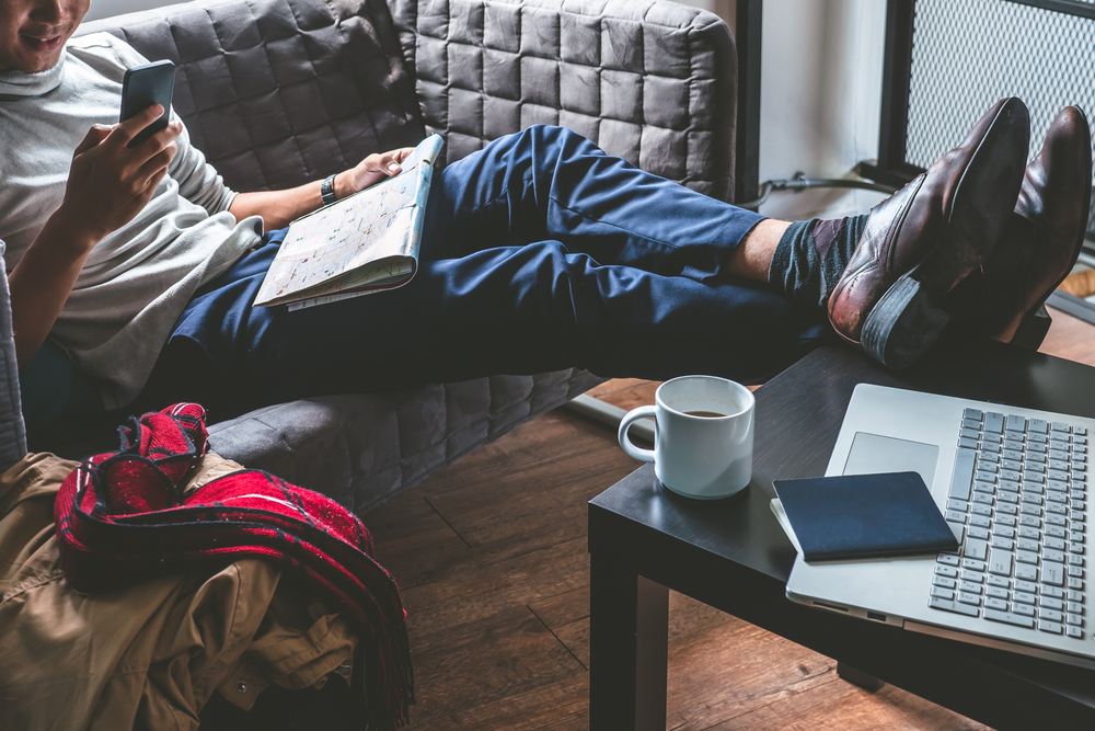 man booking travel on mobile app from couch