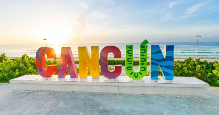 Colorful sign for Cancun in large letters with the beach in the background
