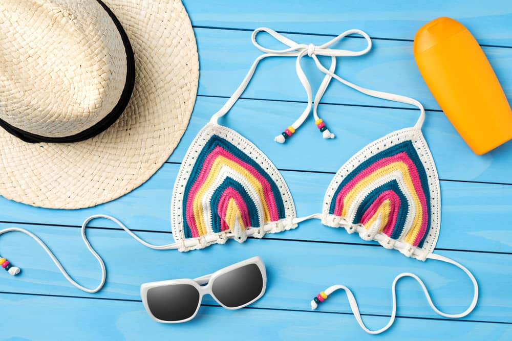 colorful bikini top, sunblock, hat, and sunglasses—all things you should pack for a trip to Cancun