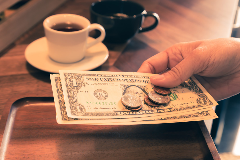 Man leaves a few dollars as tip at a cafe. Travel tip: NYCers tend to tip 15-20 percent of the bill.