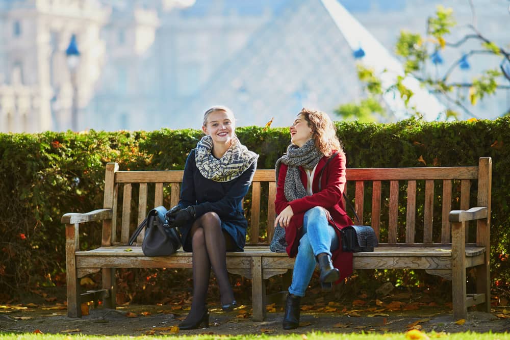 Two girls talk outside of the Louvre in Paris. Travel tip: Learning some French is helpful on your trip.