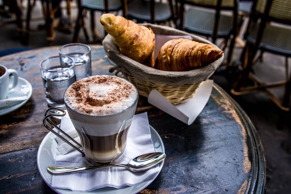 Hot chocolate and basket of croissants rest on a Paris cafe table. Travel tip: Paris food is incredible