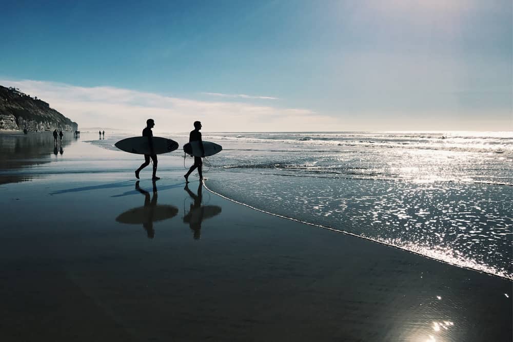 Surfers walking into the water in San Diego with their boards as the tide comes in.