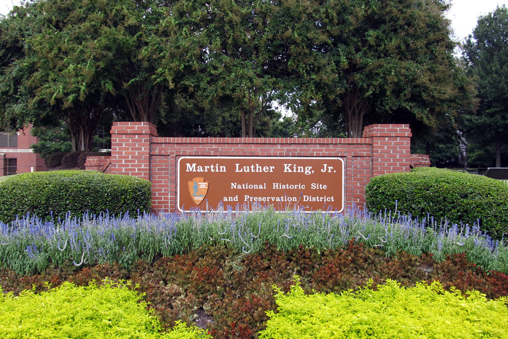 Atlanta is known for history, like the Martin Luther King, Jr. National Historic Site. Red brick gate with green hedges and purple flowers at the Martin Luther King, Jr. National Historic Site in Atlanta.