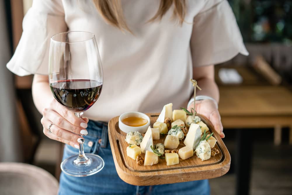 Girl wine tasting with red wine charcuterie plate and cheese board