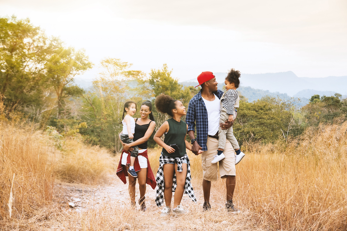 Happy mixed race big family with father, mother and child daughter walking on country road. Travel vacation concept